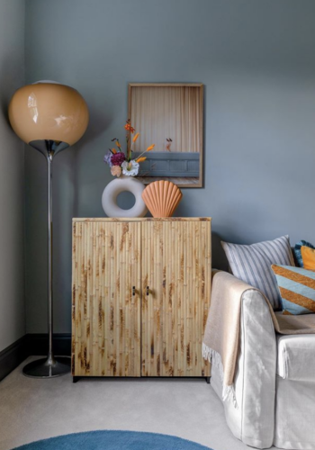 tortoiseshell bamboo covered cupboard with peach glass floor lamp, cream sofa and orange striped cushion. .interior designer Em Gurner, image by anna yanovski