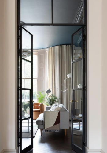 internal black framed glass doors through to living room with soft neutral tones. by frank & faber