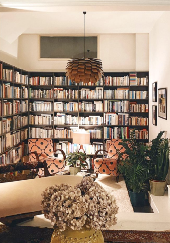 Kate Watson-Smyth's library with reading chairs in Velvet Spot Flower Jade by Orla Kiely, cream chaise, large mid-century pendant light and yellow vase with dried hydrangeas